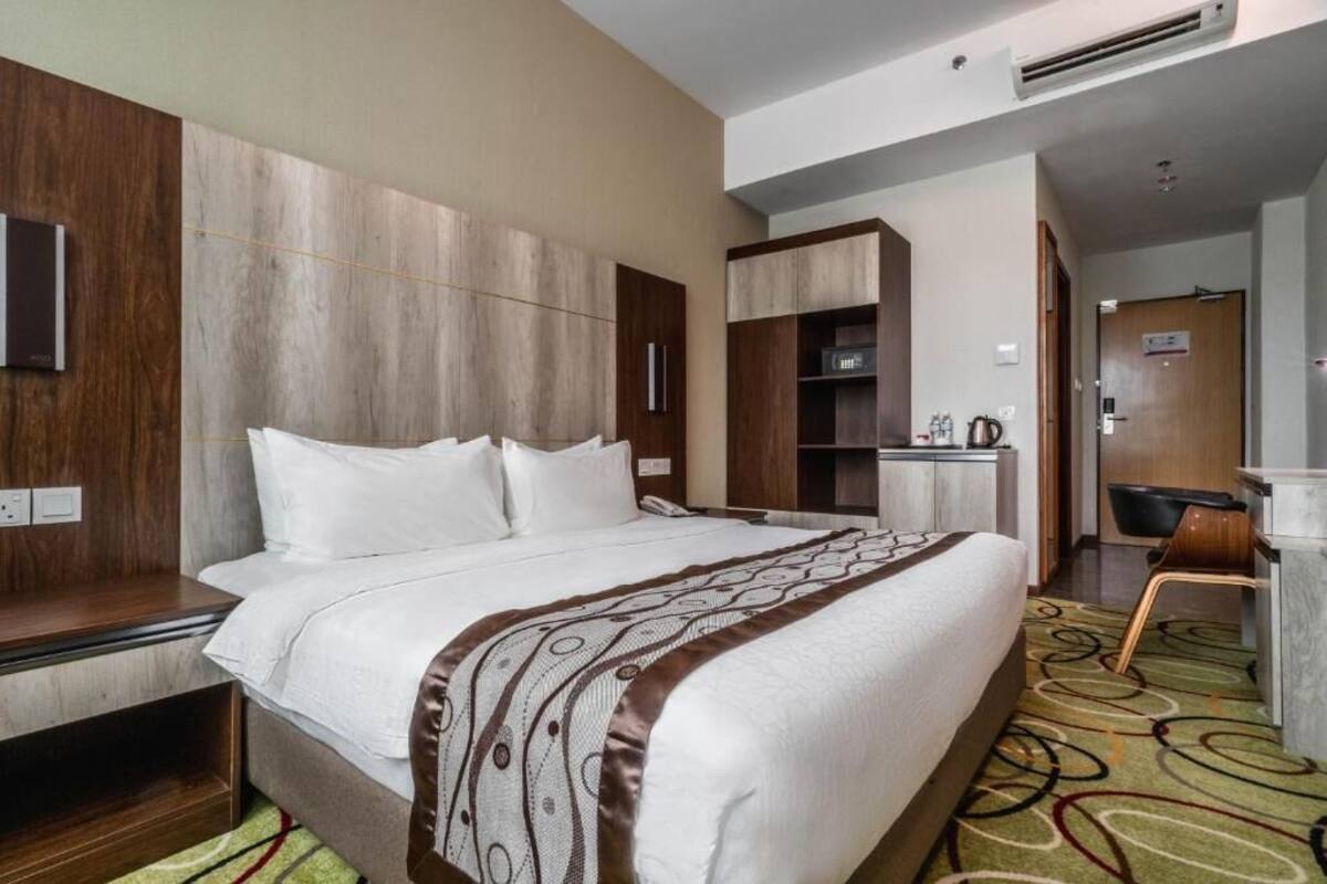 Una habitación de hotel con una cama grande, un escritorio y una kitchenette.