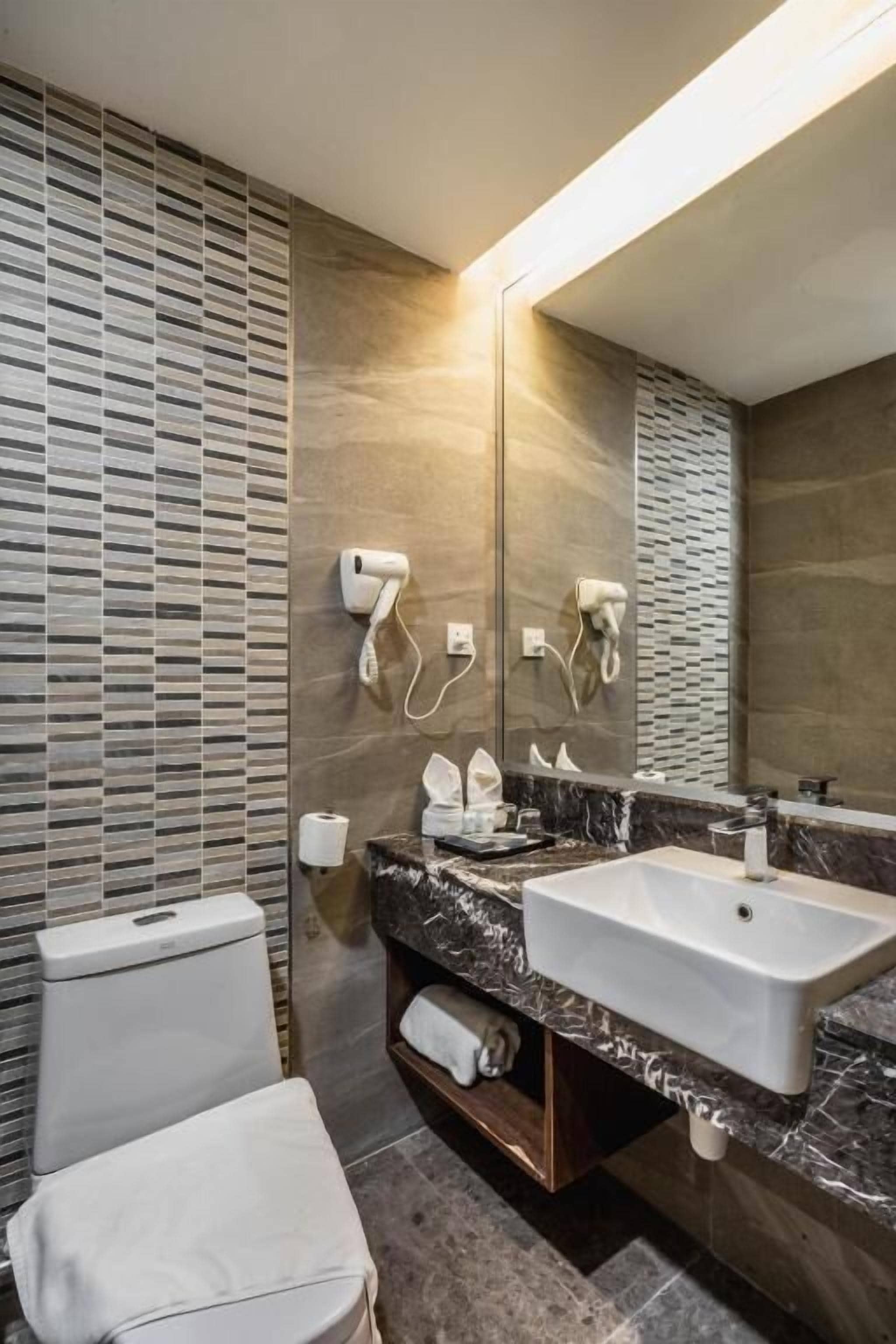 A modern bathroom with a large mirror, a sink, and a toilet.
