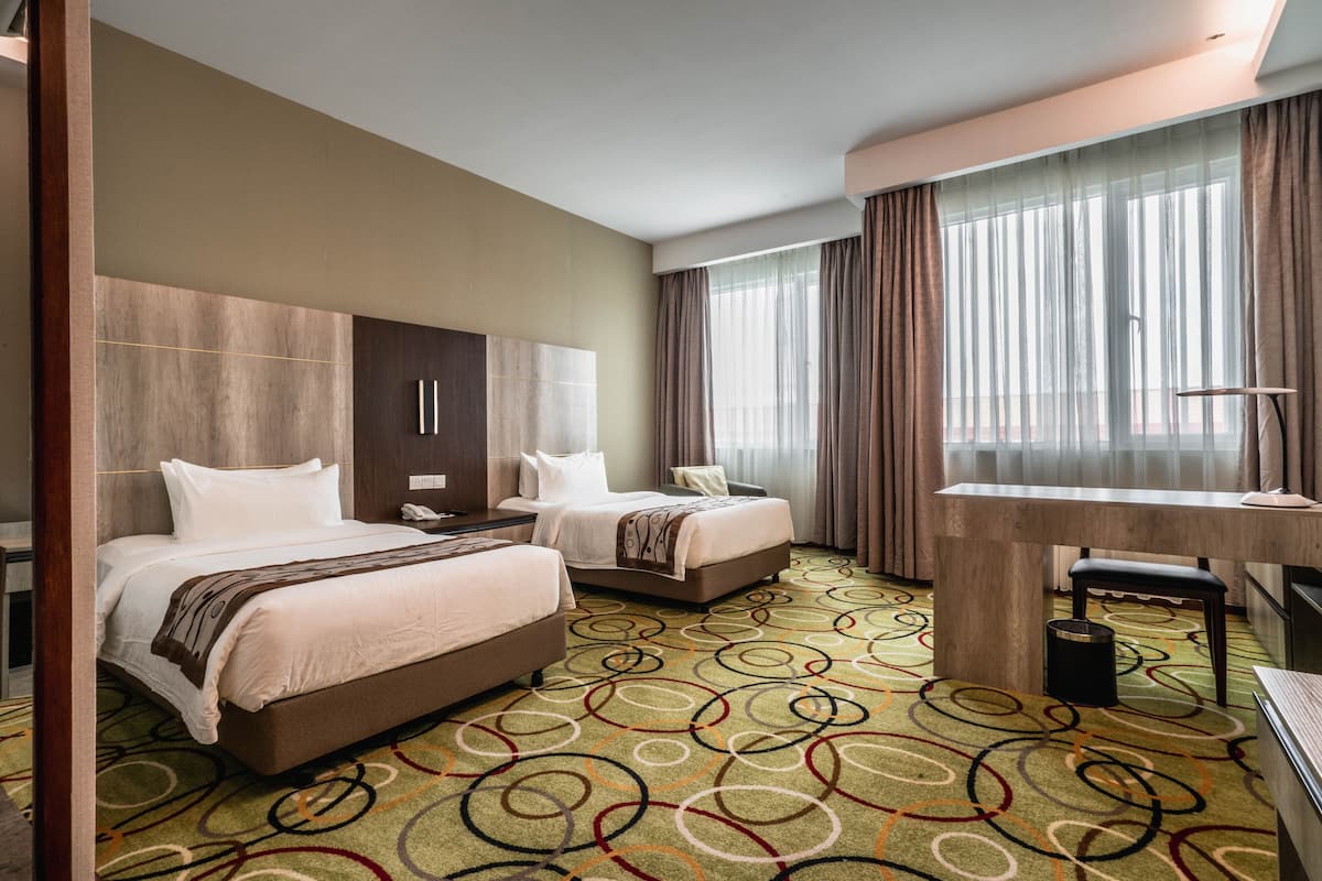 Habitación de hotel con dos camas, un escritorio y una silla.
