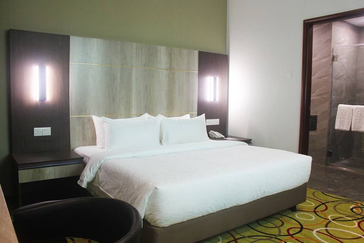 Habitación de hotel con una cama grande, un escritorio con teléfono y zona de ducha.