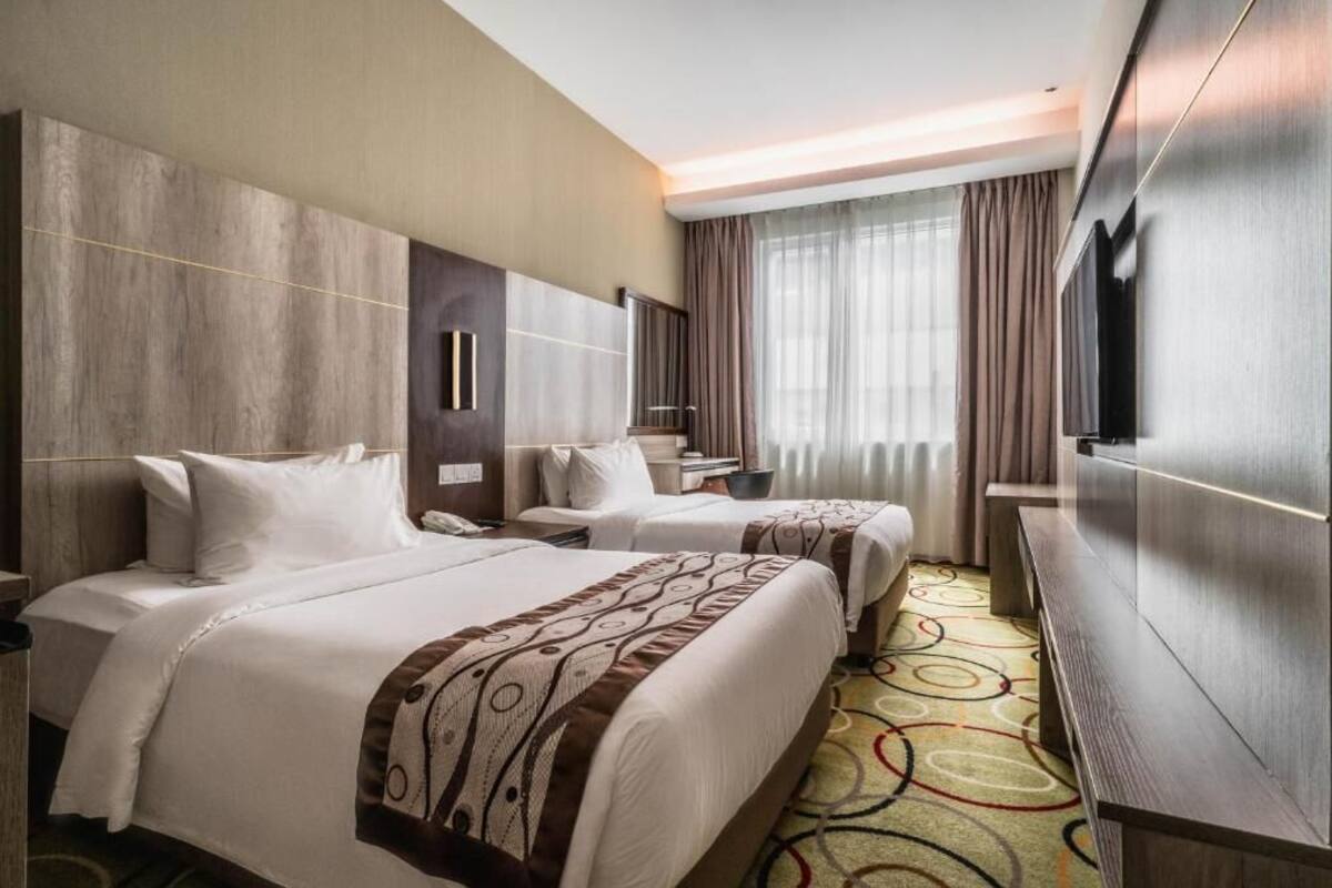 Habitación de hotel con dos camas, un televisor, un escritorio y un espejo grande.