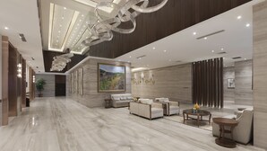 Een ruime lobby met een hoge plafond, marmeren vloeren en moderne meubels.