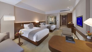 Een hotelkamer met twee bedden, een bureau, een stoel, een televisie en een lamp.