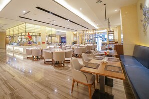 A modern restaurant with a clean, polished floor and a variety of seating options including round tables and booths.