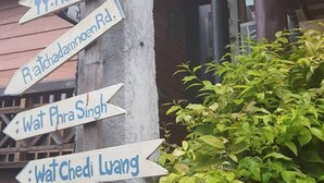 A directional signpost with multiple arrows pointing to various local attractions such as the Three Kings Museum, Art Museum, and Wat Chedi Luang. - The Commonroom CNX (Chiang Mai)