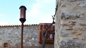 Un edificio de piedra con fachada rústica, un banco de madera y un poste de metal.