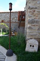 Un edificio de piedra con fachada rústica, un banco de madera y un poste de metal.