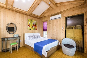 A wooden-paneled room with a bed, a desk, a chair, and an air conditioning unit.