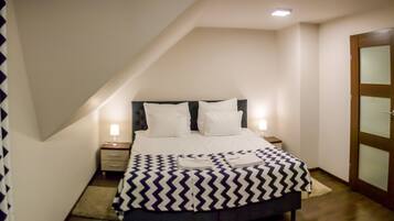 A bedroom with a bed, nightstands, a wooden door, and a patterned curtain.