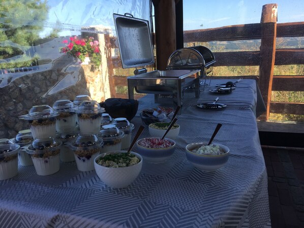 A buffet table with various food items and a grill in the background.