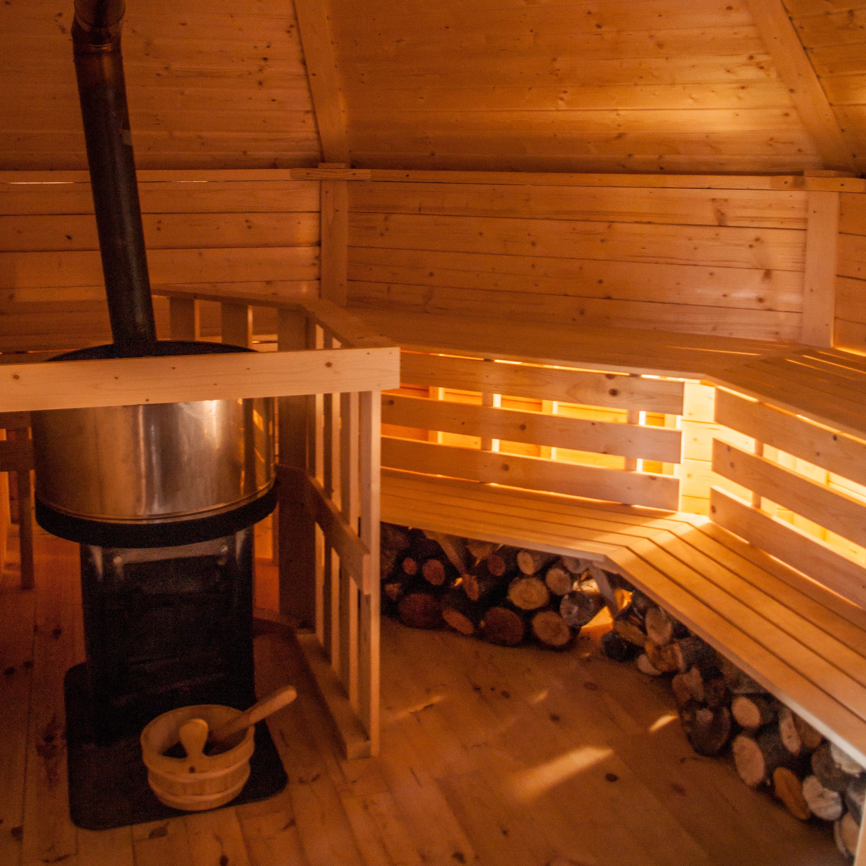 Un intérieur en bois avec un poêle, un banc et une pile de bûches.