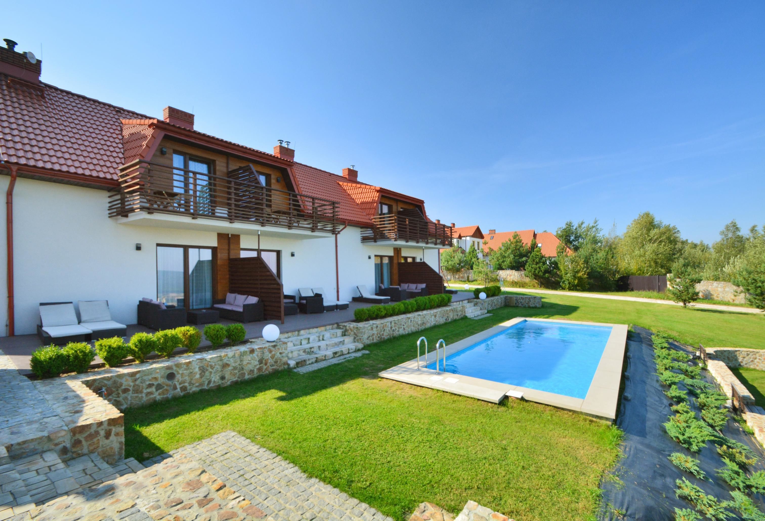 Una casa moderna con piscina, escalones de piedra y un césped cuidado.
