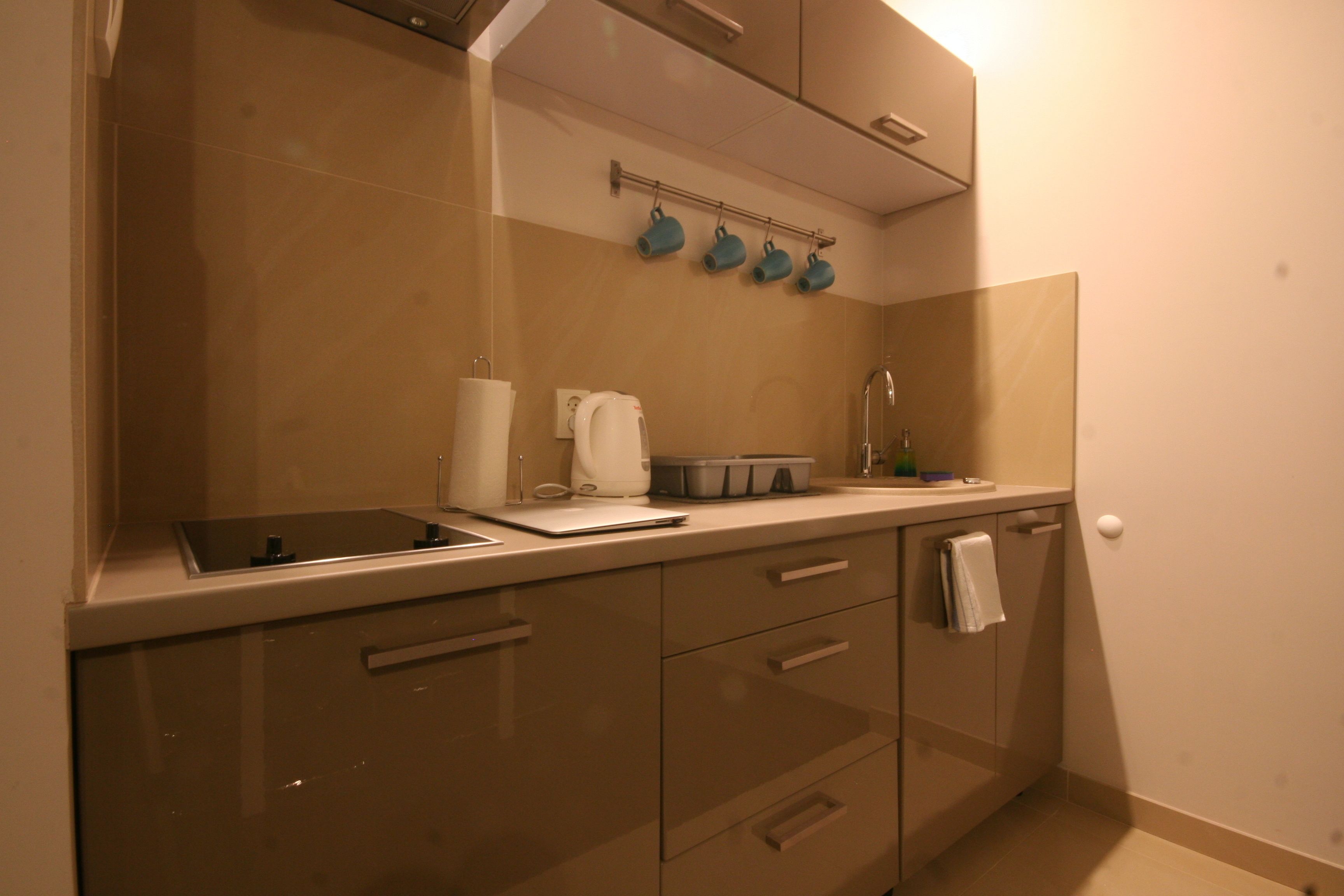 A modern kitchen with a built-in stove, a coffee machine, and a microwave. There are cabinets and a countertop with a towel hanging on the door.