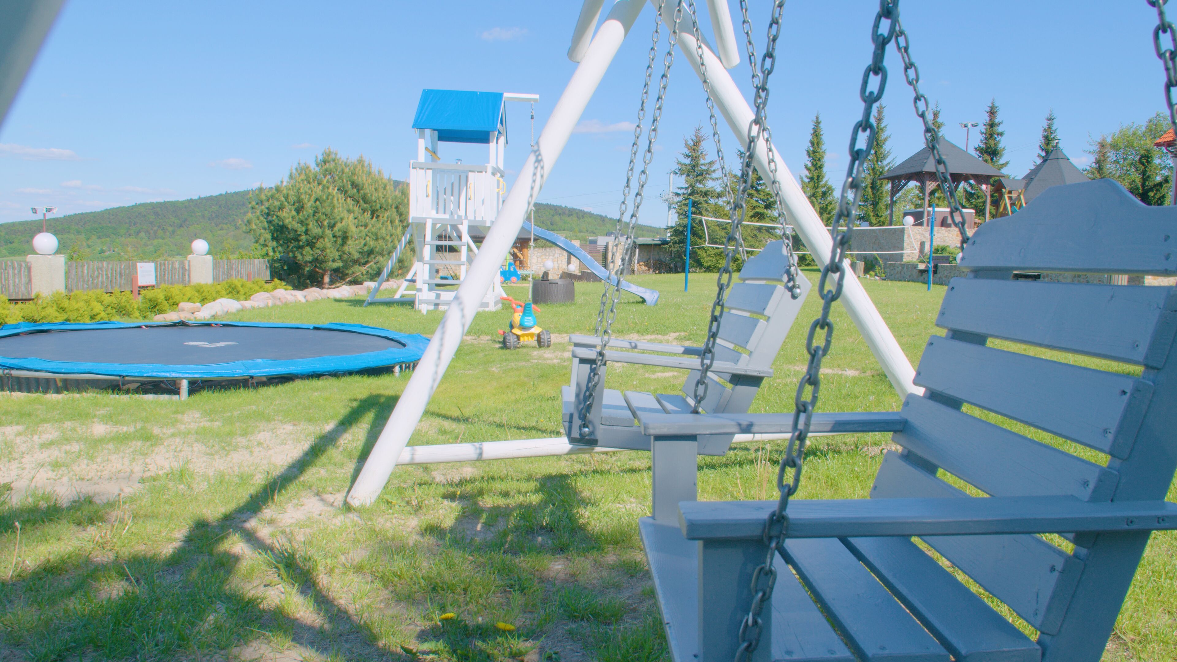 A playground with a swing set, a trampoline, and a climbing structure.