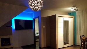 Ein modernes Wohnzimmer mit Fernseher, einem gemusterten Teppich und einem Schiebetürenschrank.