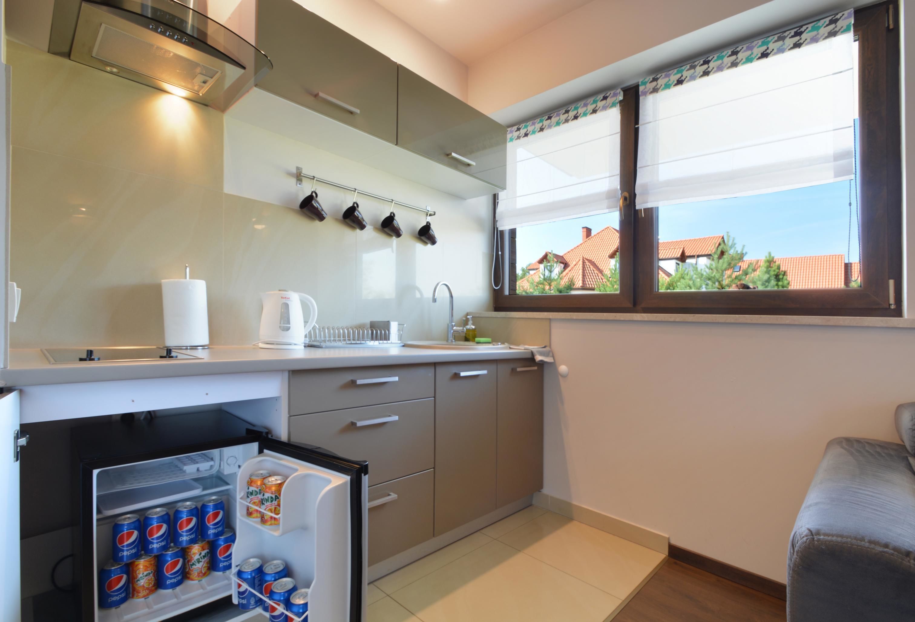 A modern kitchen with a refrigerator, a coffee maker, and a window with a view of houses.