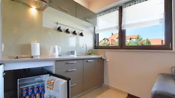 A modern kitchen with a refrigerator, a coffee maker, and a window with a view of houses.