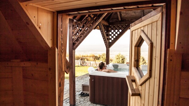 Eine Holzhütte mit Whirlpool und Blick auf die Landschaft.