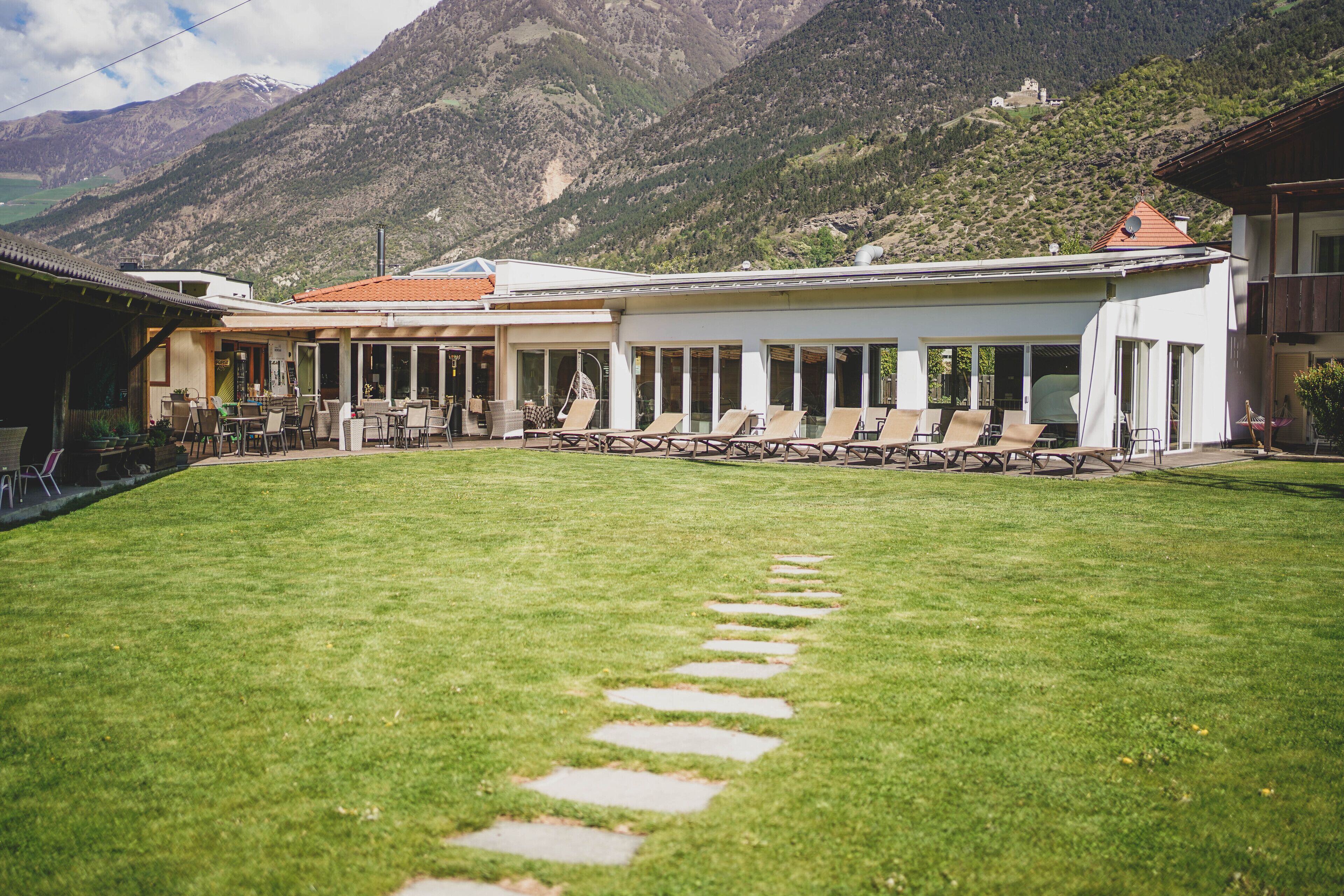 Un hôtel doté d’un patio avec des espaces de détente en plein air et un chemin de pierre menant à l’entrée.