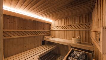 Un sauna en bois, avec des bancs, un seau et un poêle à bois.