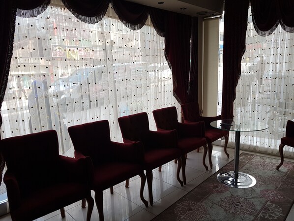 A room with a row of red upholstered chairs, a glass table, and a patterned rug. - Can Hotel (Bursa)