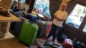 A hotel lobby with multiple suitcases, a decorative vase, and a view of parked cars outside. - Can Hotel (Bursa)