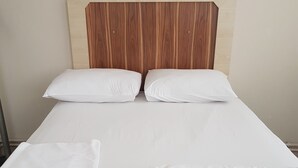 A neatly made bed with white linens, a wooden headboard, and a teal-colored bed skirt. - Can Hotel (Bursa)