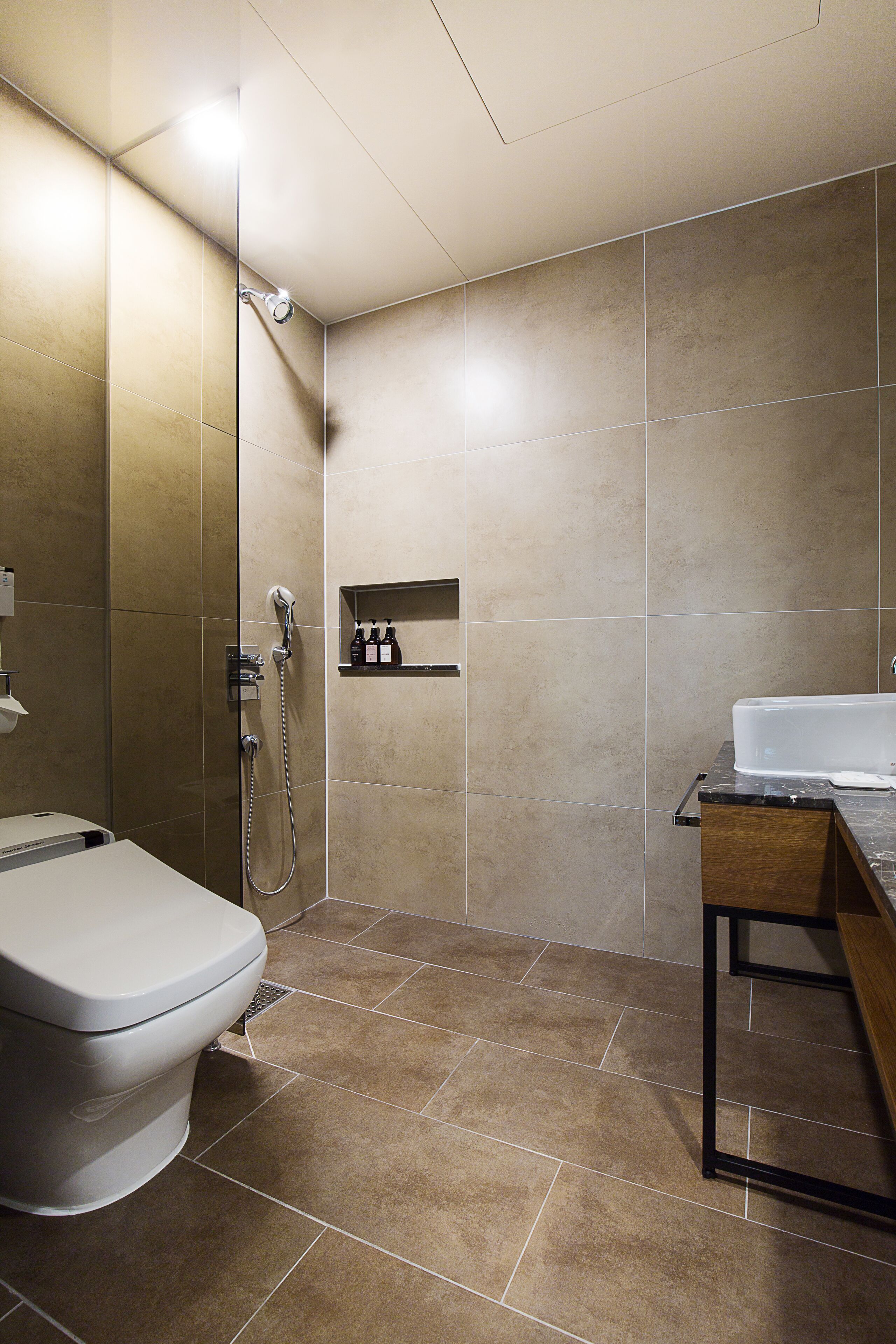 A modern bathroom with a toilet, shower, and sink.