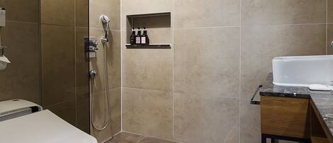 A modern bathroom with a toilet, shower, and sink.