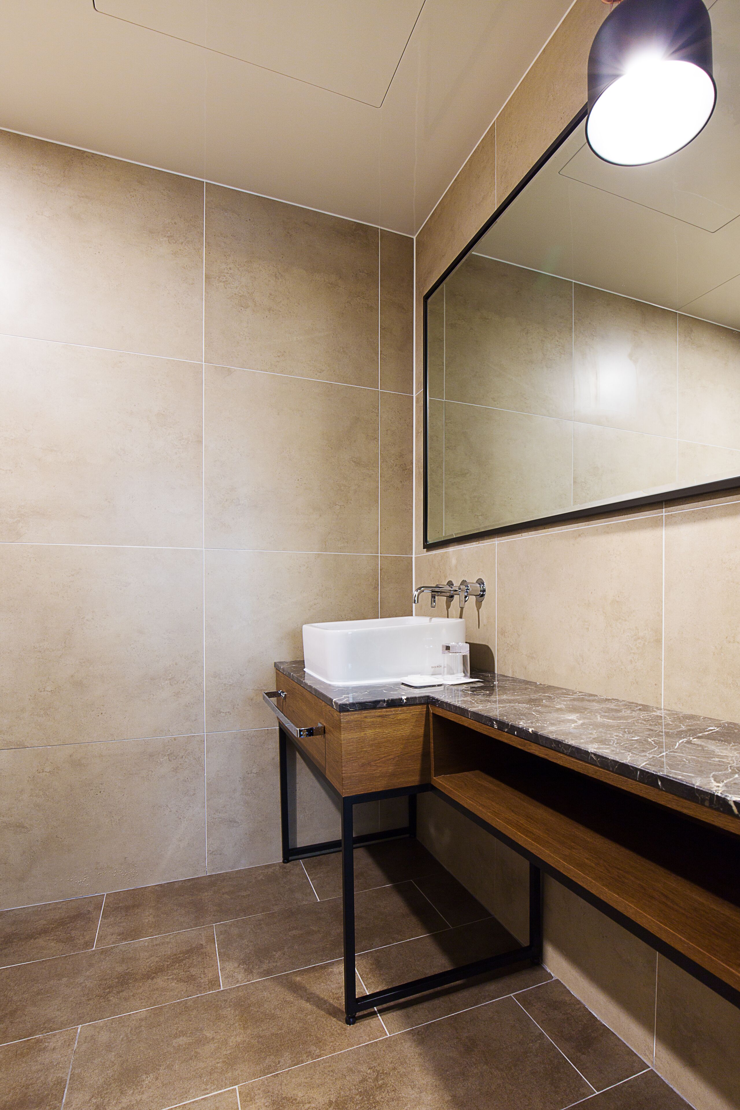 A modern bathroom with a wooden vanity, a white bathtub, and a large mirror.