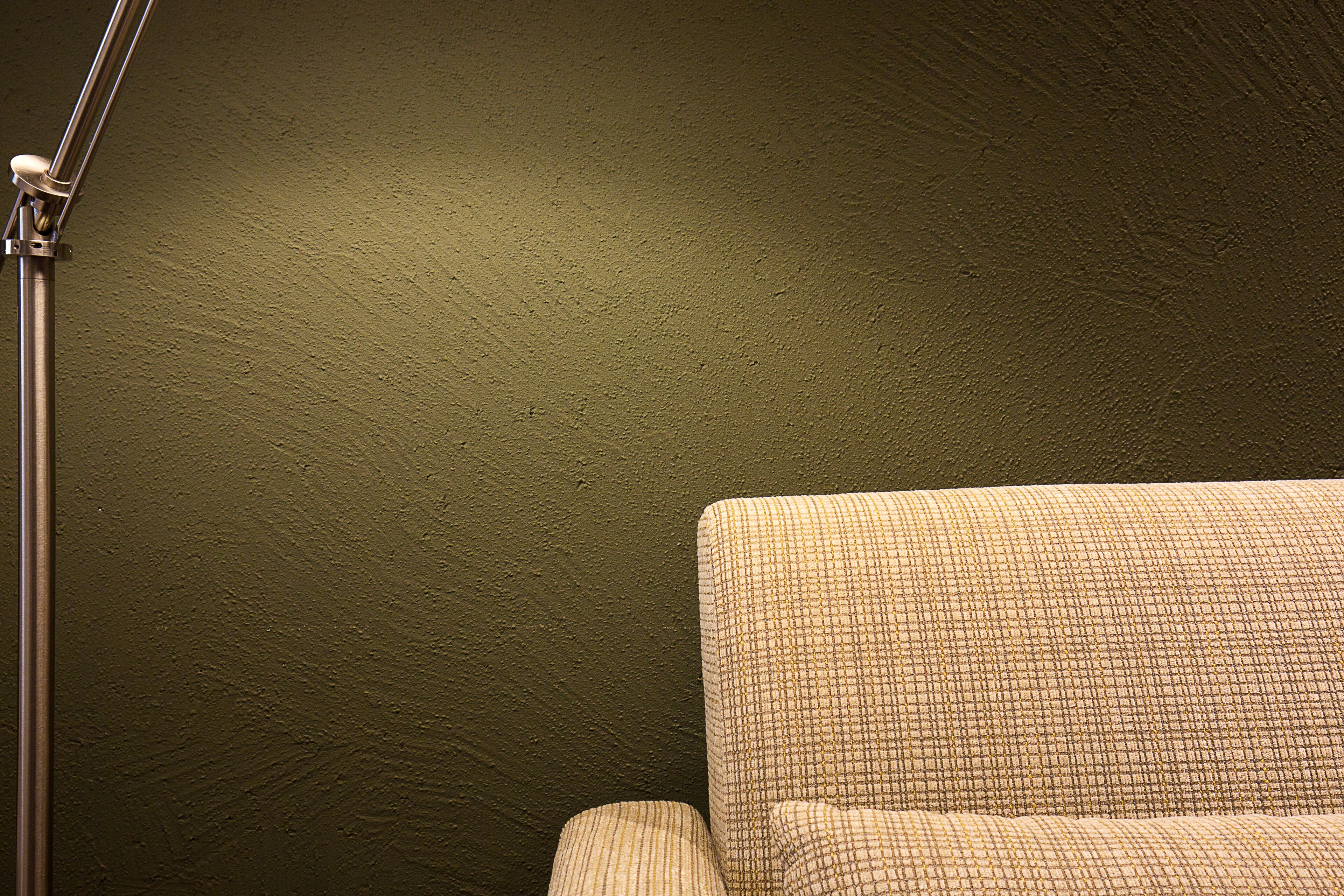 Una habitación con pared verde texturizada y un sillón estampado.