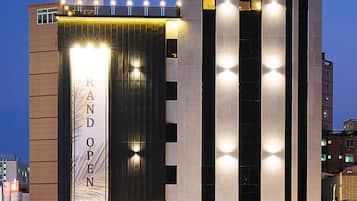 L’hôtel Brown-Dot se distingue par son enseigne bien visible, une grande enseigne verticale annonçant une « grande ouverture », et sa façade bien éclairée.