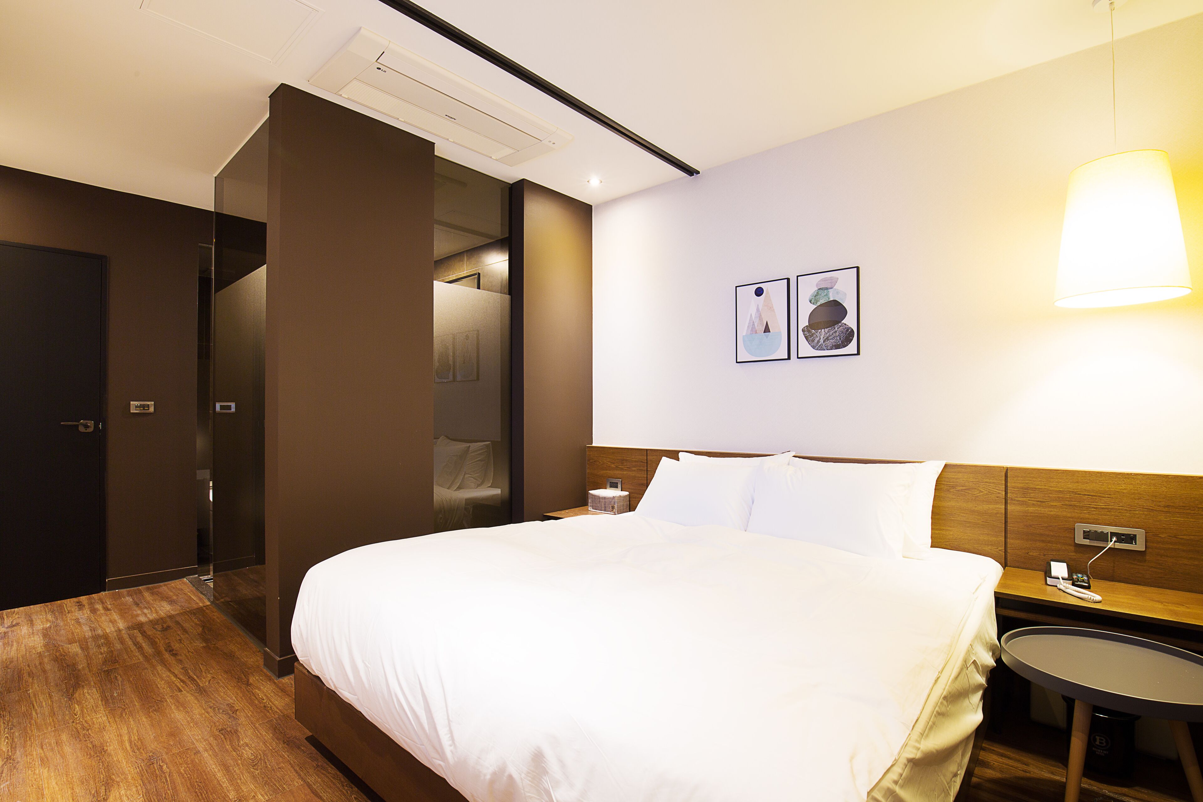 A hotel room with a large bed, a bedside table, a small round table, and a wall-mounted lamp.