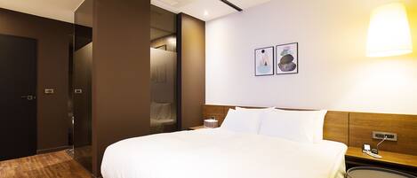 Une chambre d’hôtel avec un grand lit, une table de chevet, une petite table ronde et une lampe fixée au mur.