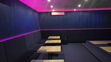 A modern cinema with dark blue walls, neon pink lighting, and multiple rows of seating.