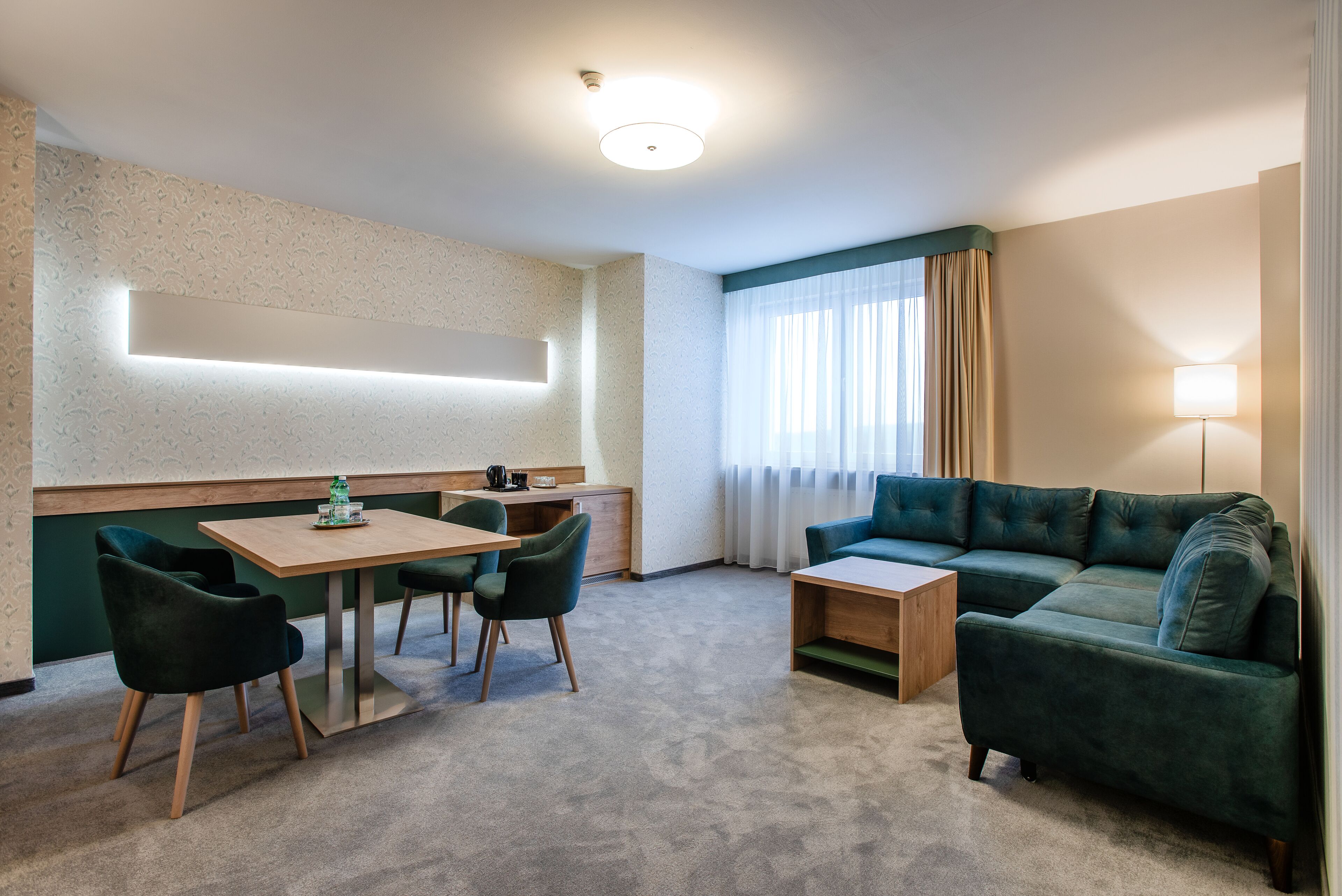 A modern hotel room with a dining area, a sofa, and a lamp.