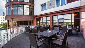 An outdoor terrace with wicker furniture and large windows offering a view of the landscape. - Hotel La Mar (Kielce)