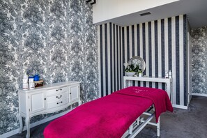 Una habitación con una cama, un tocador blanco con espejo y una pared a rayas.