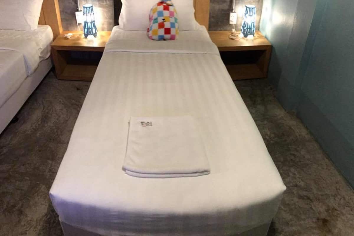 A hotel room with a single bed, two bedside tables with lamps, and a colorful pillow.