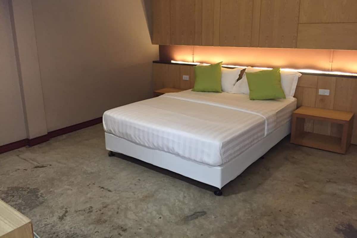 A bedroom with a bed, nightstands, and a wooden headboard.