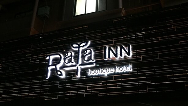 Señal de hotel con el nombre 'RaTa INN boutique hotel' iluminado durante la noche.