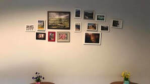 Una habitación con dos mesas redondas de madera, cada una con una pequeña planta en maceta. Las paredes están decoradas con una serie de fotografías enmarcadas.
