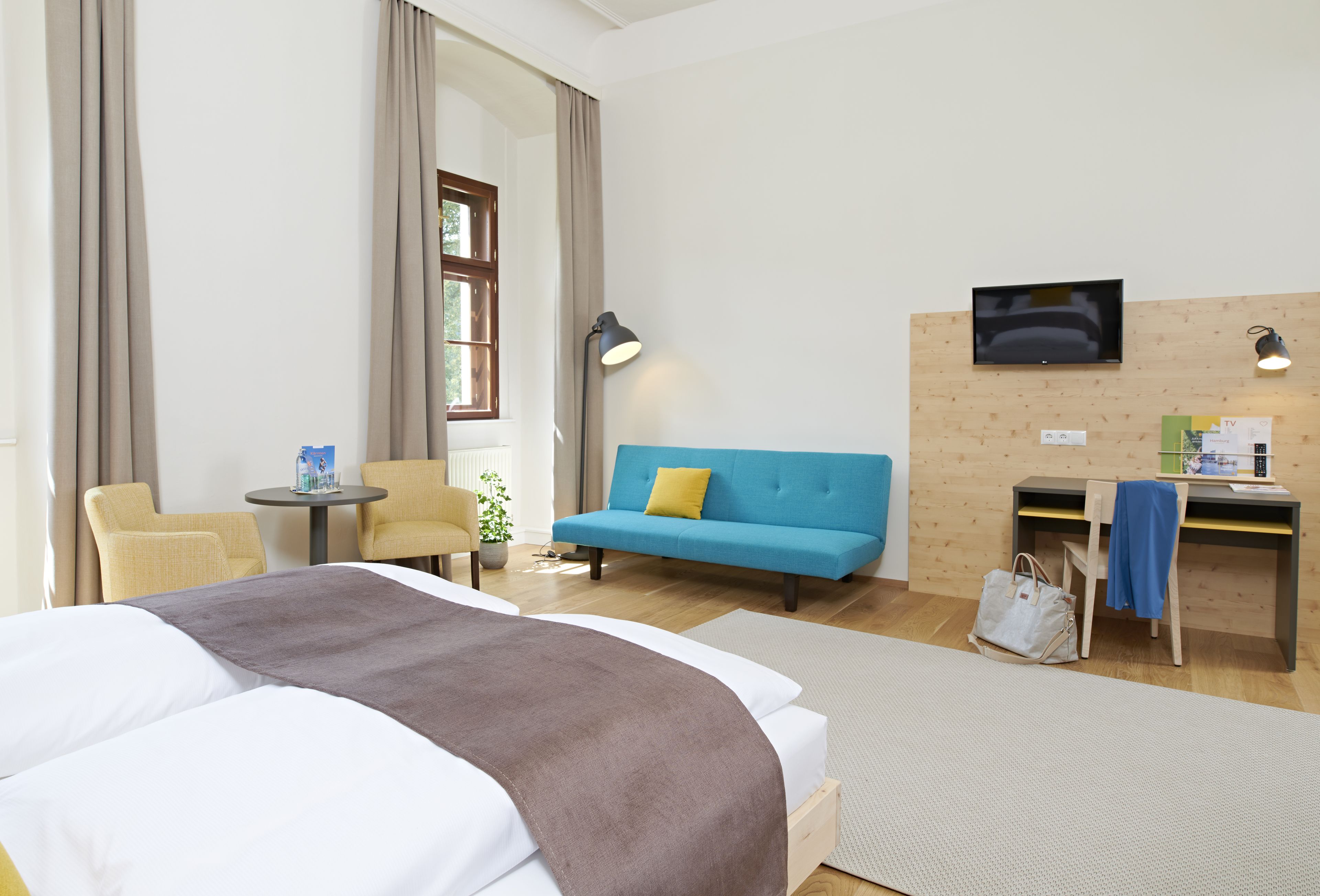 Une chambre d’hôtel avec un lit, un canapé, un bureau, une télévision et une chaise.