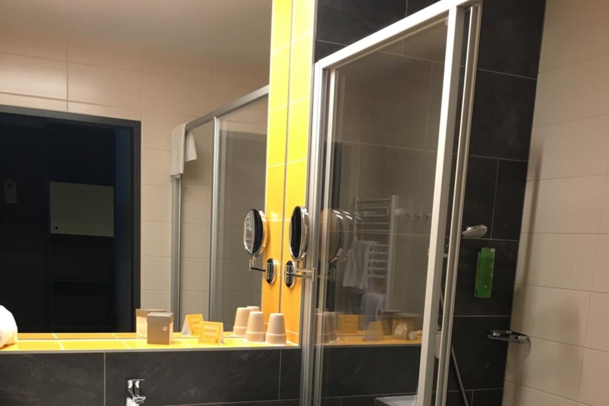 A modern bathroom with a glass-enclosed shower, a white sink, and a mirror with two round mirrors.