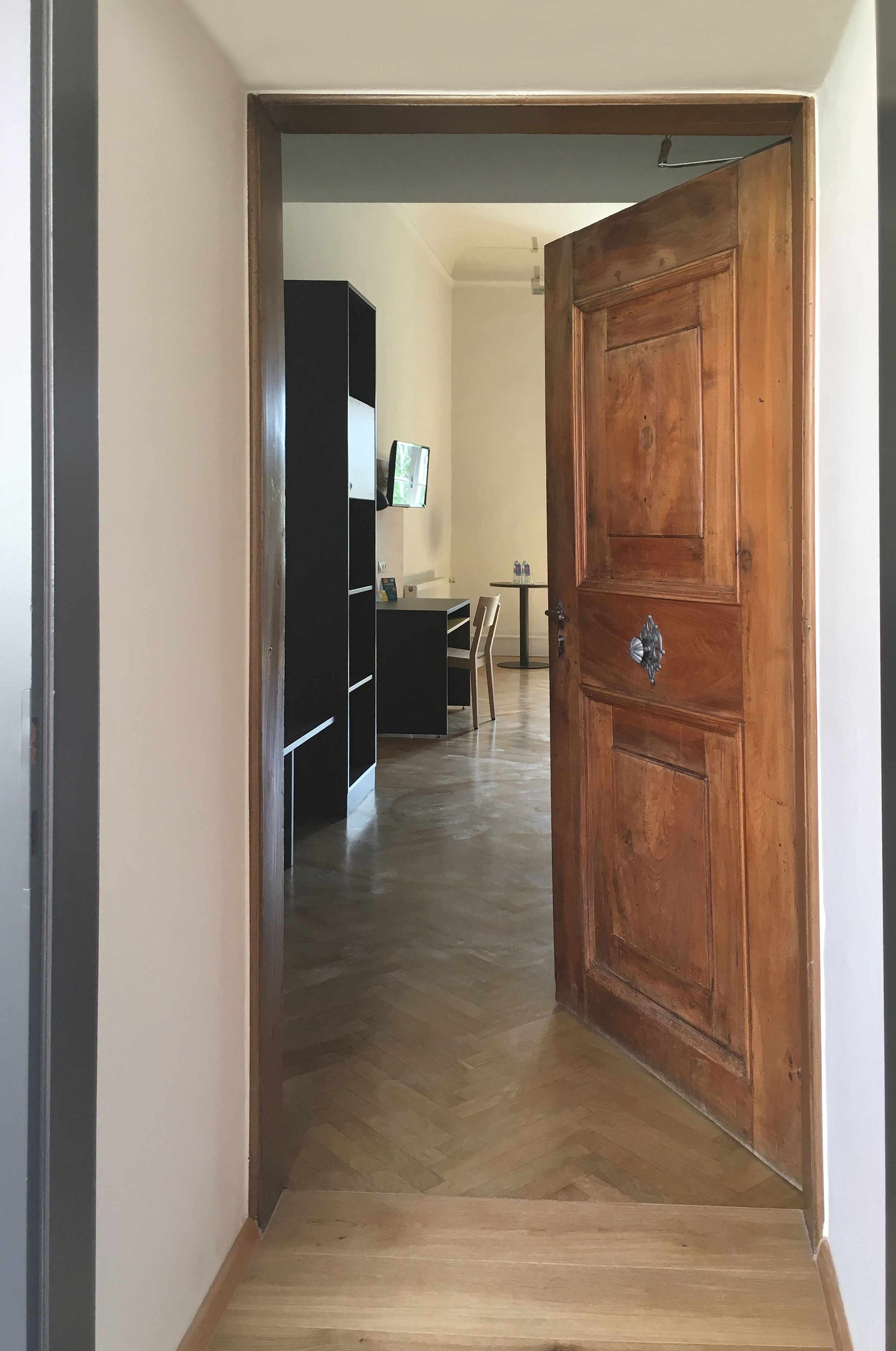 Puerta de madera que da a una habitación con suelo en dibujo de espiga.