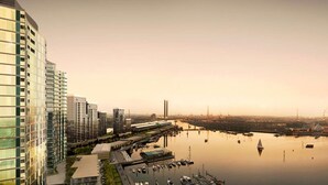 A high-rise building with a glass facade, a marina with boats, and a distant view of a city skyline. - Melbourne Docklands Concavo Seaview Apartment (Docklands)