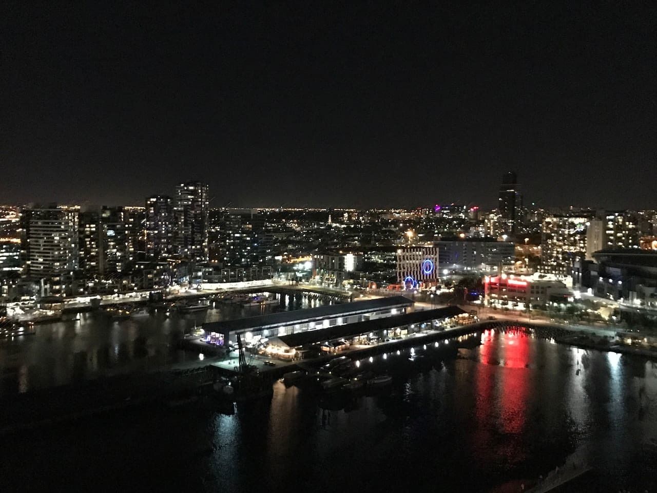 Un paisaje urbano nocturno con edificios iluminados, una ribera y un puente.
