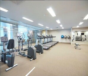 Een sportschool met loopbanden, elliptische trainers en losse gewichten.