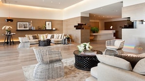 A spacious living area with a modern sofa set, a coffee table, and a seating area with a wicker chair. - Melbourne Docklands Convesso Seaview Apartment (Docklands)