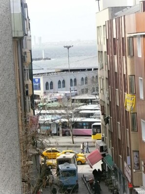 A narrow street with parked vehicles, including buses and cars, and buildings with balconies. - Hotel Nova (Istanbul)